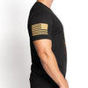 Black t-shirt with gold American flag design on sleeve, worn by a person against a white background