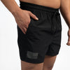 Black shorts with a small flag patch on a plain background