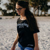 Woman wearing a black t-shirt with text on a sandy background