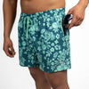 Person wearing teal floral swim shorts on a white background