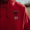 Red hoodie with a black and white emblem on the chest.