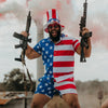 Person wearing an American flag shirt and shorts, holding two rifles with smoke in the background