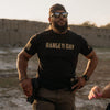 Man wearing a black t-shirt with 'RANGE DAY' text, sunglasses, and a cap in an outdoor setting.
