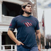 Man wearing a blue t-shirt with a graphic design, standing outdoors.