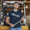 Man holding a wrench in front of a forklift in an industrial setting