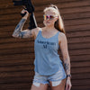 Person wearing a 'American AF' tank top holding a rifle against a wooden background