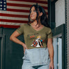 Woman wearing a green t-shirt with a graphic design in front of an American flag.