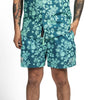 Teal floral-patterned shorts worn by a person on a white background