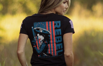 Woman wearing a black t-shirt with a graphic design and the word 'REBEL' outdoors.