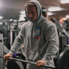 Person wearing a gray hoodie with a logo in a gym setting