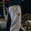 Person wearing gray sweatpants with a skull design and text in a garage setting