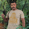 Man wearing a t-shirt with a graphic design and text, holding a toy gun in a forest setting.