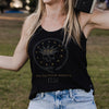 Person wearing a black tank top with a design and text, standing outdoors.