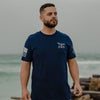 Man wearing a navy blue t-shirt with a logo on a beach