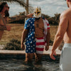 Man wearing an eagle mask and American flag clothing standing in a pool with others.