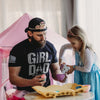 Man wearing a 'Girl Dad' shirt interacting with a young girl in a playroom.