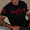 A man wearing a black short-sleeve t-shirt with 'Strokes COUNT' printed in red across the chest and a red American flag graphic on the right sleeve.