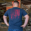 Man wearing a blue t-shirt with a red American flag design in a workshop setting.