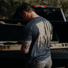 Man wearing a t-shirt with an American flag design, standing next to an open truck bed.