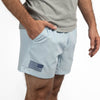Light blue shorts with an American flag patch worn by a person on a white background