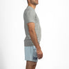 Man wearing a gray t-shirt and light blue shorts on a white background