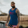Man wearing a blue tank top with a red graphic and American flag shorts, standing outdoors.