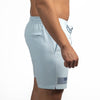 Light gray swim shorts with a small flag design on a white background