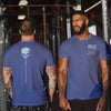 Two men wearing blue t-shirts with different designs, one with a skull and the other with an American flag, in a gym setting.