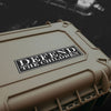 Beige hard-shell case with 'DEFEND THE CHILDREN' sticker on a dark background