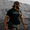 Man wearing a black t-shirt with 'DEFEND THE CHILDREN' text, standing in a desert-like environment.