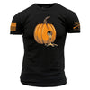 A black short-sleeve t-shirt with a graphic of an orange pumpkin on the chest, with a small skull inside the pumpkin and orange dripping details. The left sleeve features a distressed orange American flag, and the right sleeve has orange text and crossed rifles.