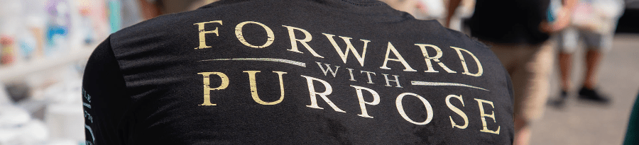 Person wearing a black t-shirt with 'Forward with Purpose' text on the back.