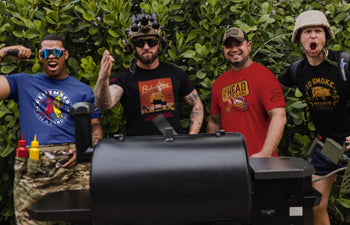Four men posing with a barbecue grill outdoors